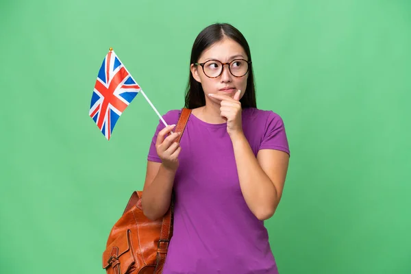 持英国国旗的年轻亚洲妇女 背景偏僻 有疑问 有想法 — 图库照片