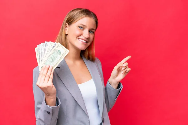 Jovem Negócio Caucasiano Mulher Segurando Dinheiro Isolado Fundo Vermelho Apontando — Fotografia de Stock