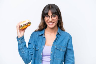 Beyaz arka planda izole edilmiş hamburgerini elinde tutan beyaz bir kadın.