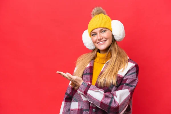 Νεαρή Όμορφη Γυναίκα Φορώντας Muffs Χειμώνα Απομονώνονται Κόκκινο Φόντο Παρουσιάζοντας — Φωτογραφία Αρχείου