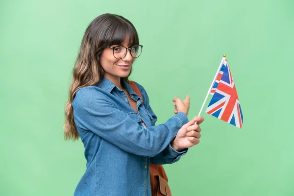 Mladá Běloška Drží Britskou Vlajku Nad Izolovaným Pozadím Ukazující Zpět — Stock fotografie