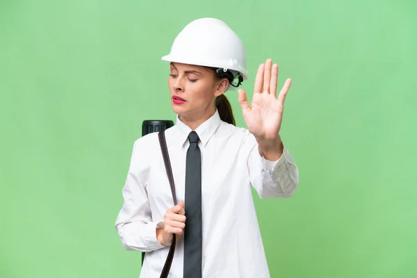 年轻的女建筑师头戴头盔 拿着设计图 在孤立的背景下做着停下来的手势 很失望 — 图库照片