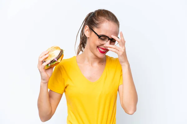 Młoda Kaukaska Kobieta Trzyma Hamburgera Białym Tle Śmiejąc Się — Zdjęcie stockowe