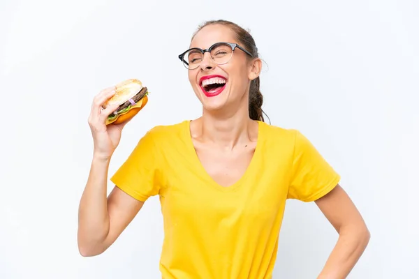 Młoda Kaukaska Kobieta Trzyma Hamburgera Odizolowanego Białym Tle Pozującego Rękami — Zdjęcie stockowe