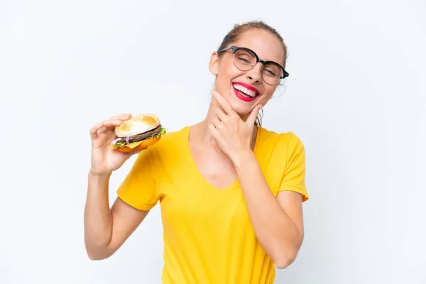 Młoda Kaukaska Kobieta Trzyma Hamburgera Białym Tle Szczęśliwy Uśmiechnięty — Zdjęcie stockowe