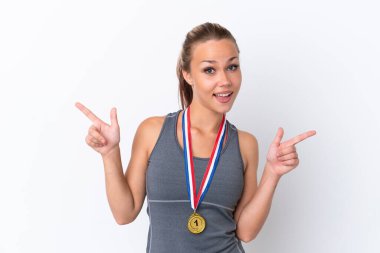 Beyaz arka planda madalyaları olan genç bir Rus kızı parmak uçlarını işaret ediyor ve mutlu.