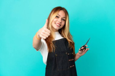 Genç kuaför kız soyutlanmış mavi bir geçmişi var. Başparmakları havada. Çünkü iyi bir şey oldu.