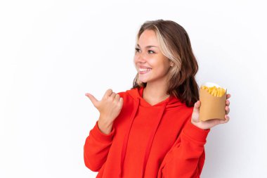 Beyaz arka planda izole edilmiş kızartma cipsleri tutan genç bir Rus kızı bir ürünü sunmak için kenarı işaret ediyor.