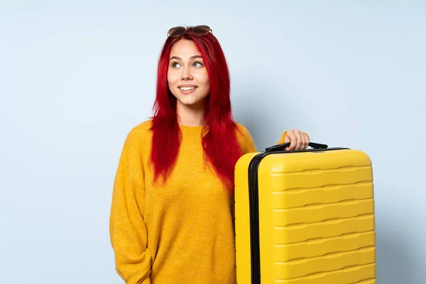 旅行女孩提着一个蓝色背景的手提箱 一边想办法一边抬头看 — 图库照片