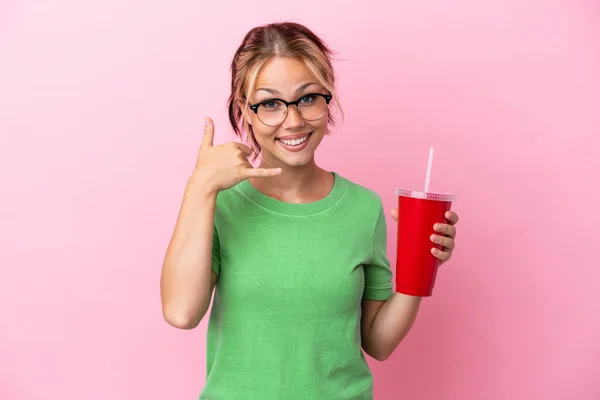 stock image Young Russian woman holding a refreshment isolated on pink background making phone gesture. Call me back sign