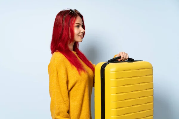 带着一个蓝色背景的手提箱的女旅行家 横向放置 — 图库照片