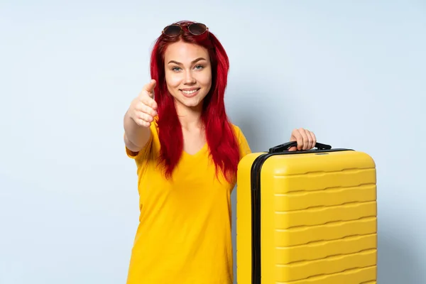 旅行的女孩拿着一个蓝色背景的手提箱 握着她的手和她握手 因为她把它关上了不少 — 图库照片