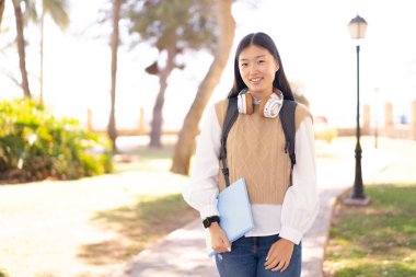 Dışarıdaki güzel Çinli kadın elinde mutlu bir ifadeyle bir defter tutuyor.