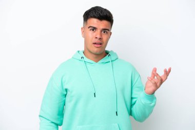 Beyaz arka planda izole edilmiş beyaz, yakışıklı genç bir adam şüpheli hareketlerde bulunuyor.