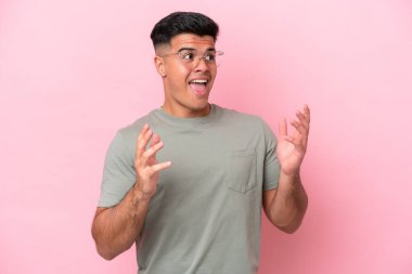 Pembe arka planda yalıtılmış beyaz, yakışıklı, şaşırtıcı bir yüz ifadesi olan genç adam.