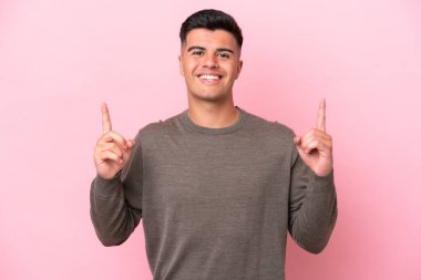 Pembe arka planda izole edilmiş beyaz, yakışıklı genç adam harika bir fikre işaret ediyor.