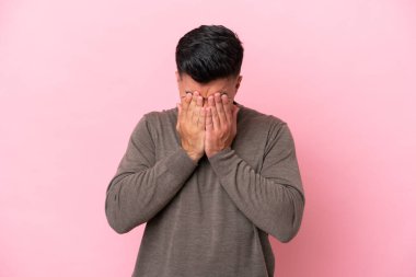 Pembe arka planda izole edilmiş, yorgun ve hasta bir ifadeyle genç, beyaz, yakışıklı bir adam.