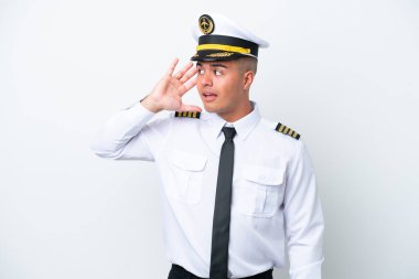 Uçak pilotu, beyaz arka planda izole edilmiş beyaz bir adam, elini kulağına koyarak bir şeyler dinliyor.