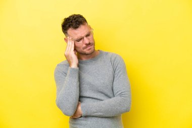 Sarı arka planda yalnız ve başı ağrıyan beyaz, yakışıklı bir genç.