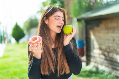 Elma ve çörek tutan beyaz bir kadın.