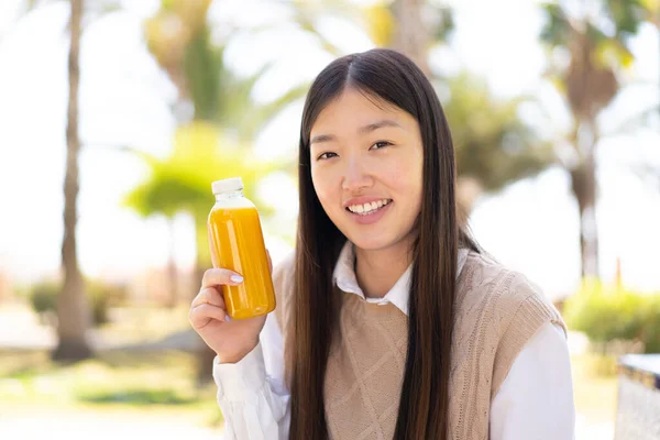 Όμορφη Κινέζα Που Κρατάει Ένα Χυμό Πορτοκάλι Στην Ύπαιθρο Χαμογελώντας — Φωτογραφία Αρχείου