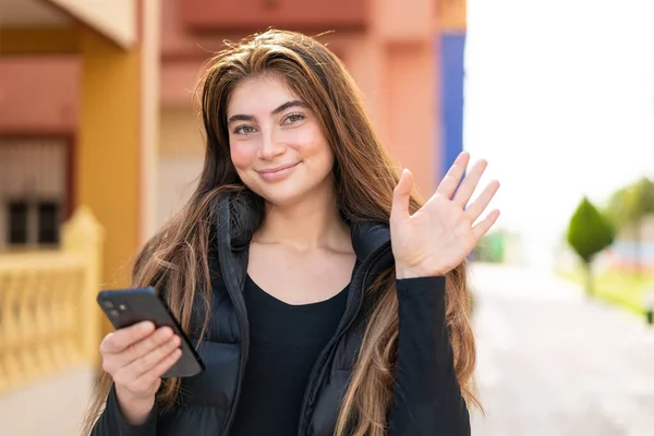 Mladý Pěkný Kavkazský Žena Pomocí Mobilního Telefonu Venku Salutování Rukou — Stock fotografie