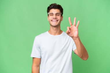 Soyutlanmış geçmişi olan beyaz, yakışıklı bir adam mutlu ve parmaklarıyla üçe kadar sayıyor.