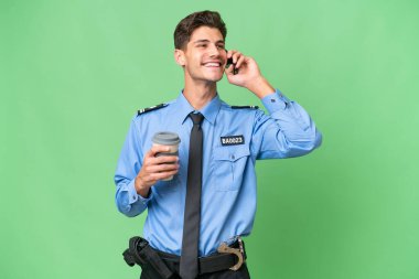 Arka planda izole edilmiş genç bir polis kahve ve bir cep telefonu tutuyor.