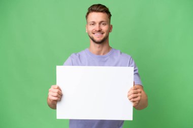 Sarışın, beyaz bir adam izole edilmiş bir arka planda elinde mutlu bir ifadeyle boş bir levha tutuyor.