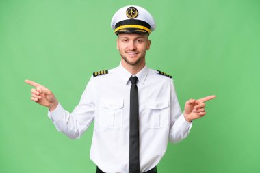 İzole edilmiş arka planda uçak pilotu parmak uçlarını işaret ediyor ve mutlu.