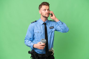 Arka planda izole edilmiş genç bir polis kahve ve bir cep telefonu tutuyor.