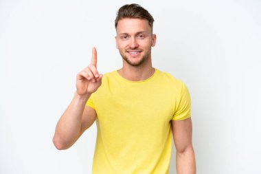 Beyaz arka planda izole edilmiş genç sarışın beyaz adam en iyinin işareti olarak parmağını kaldırıyor.