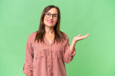 Orta yaşlı, beyaz bir kadın, arka planda izole edilmiş bir şekilde, bir ilan vermek için fotokopi makinesini avucunun içinde tutuyor.