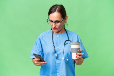 Orta yaşlı bir hemşire, izole edilmiş bir geçmişi var. Elinde kahve ve cep telefonu var.