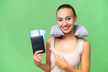Şişirilebilir Seyahat Yastığı ile izole edilmiş arka planı olan genç bir Arap kadın bir ürün sunmak için kenarı işaret ediyor.