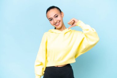 Genç Arap kadın mavi arka planda soyutlanmış gururlu ve kendini beğenmiş