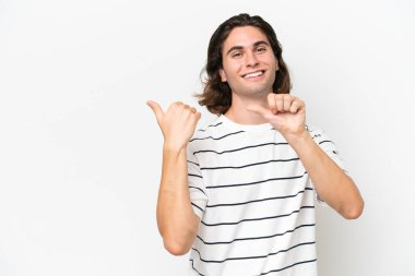 Beyaz arka planda izole edilmiş genç yakışıklı bir adam bir ürün sunmak için kenarı işaret ediyor.