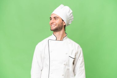 Genç, yakışıklı aşçı, soyutlanmış arka planda.