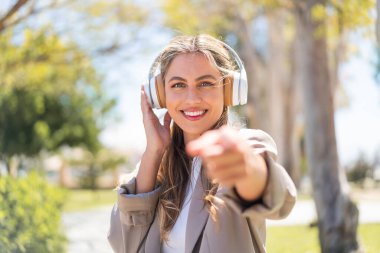 Güzel sarışın Uruguaylı kadın müzik dinliyor ve ön tarafı işaret ediyor.