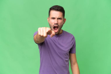 İzole edilmiş arka planda genç, yakışıklı beyaz adam hayal kırıklığına uğramış ve ön tarafı işaret ediyor.