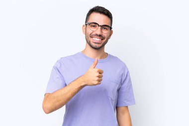 Beyaz arka planda izole edilmiş genç beyaz bir adam baş parmak hareketi yapıyor.