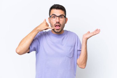 Beyaz arka planda izole edilmiş genç beyaz bir adam telefon jesti yapıyor ve şüpheli.