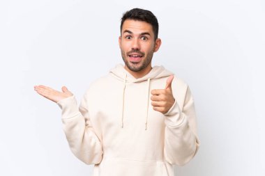 Beyaz arka planda izole edilmiş genç beyaz bir adam, bir ilan vermek ve onaylamak için avucunda hayali bir kopyalama alanı tutuyor.