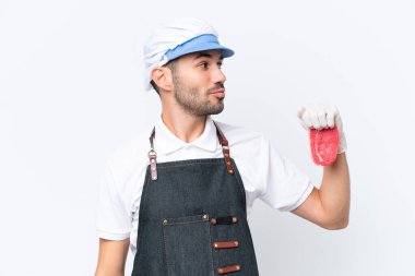 Kasap beyaz önlük takmış ve izole edilmiş beyaz arka planda taze et servis ediyor.