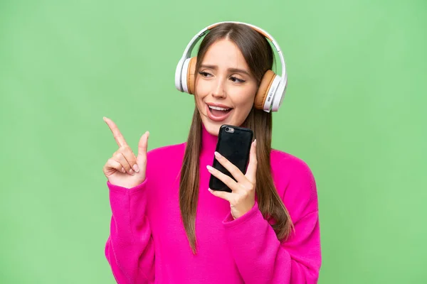 Jonge Mooie Kaukasische Vrouw Geïsoleerde Achtergrond Luisteren Muziek Met Een — Stockfoto