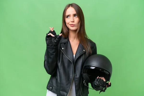 年轻漂亮的高加索女人 头戴摩托车头盔 背负孤立的背景 手指头交叉 祝福好运 — 图库照片