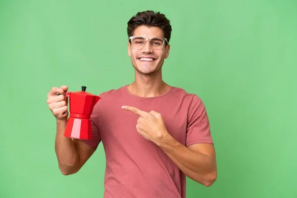 Jonge Kaukasische Man Houdt Koffie Pot Geïsoleerde Achtergrond Wijzen — Stockfoto