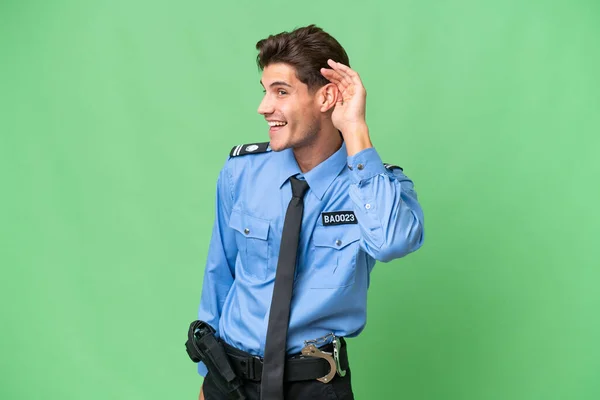 Młody Policjant Odosobnionym Pochodzeniem Słucha Czegoś Przykładając Rękę Ucha — Zdjęcie stockowe