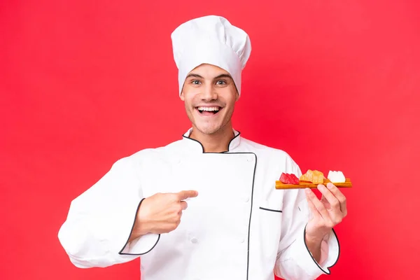 Junge Kaukasische Koch Mann Hält Sashimi Isoliert Auf Rotem Hintergrund — Stockfoto