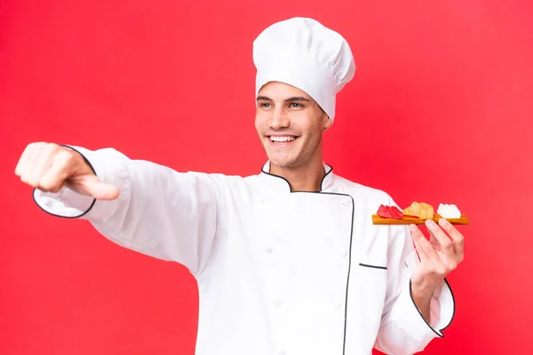 Joven Chef Caucásico Hombre Sosteniendo Sashimi Aislado Sobre Fondo Rojo — Foto de Stock